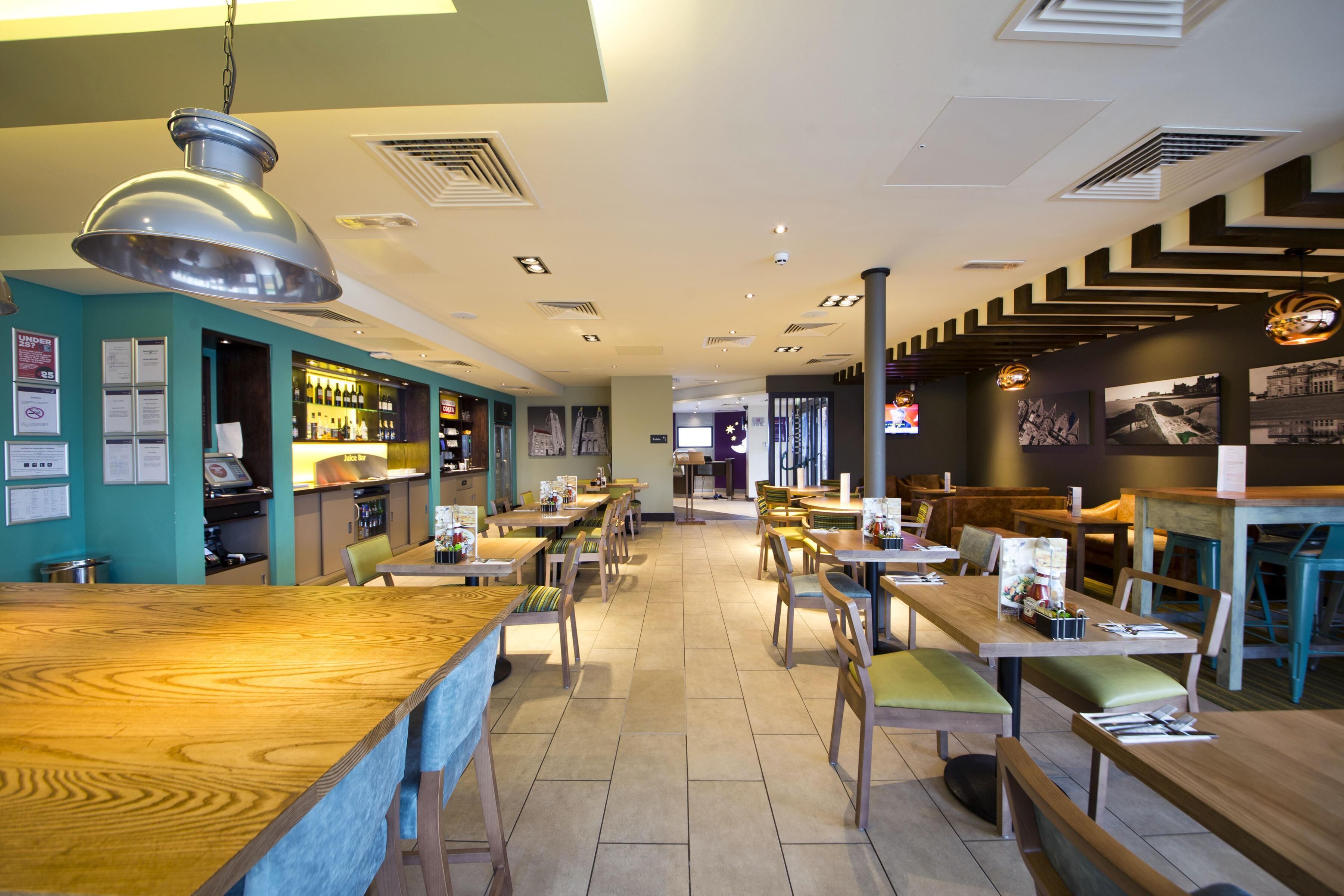 A restaurant interior with wooden tables and chairs, a bar area, and a counter.
