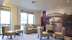 Eine Hotelhalle mit Sitzbereichen, einem großen Fenster und einem Wandgemälde einer Brücke.