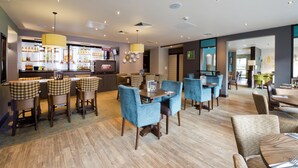 Eine Hotelhalle mit Barbereich, Sitzgelegenheiten und einer Rezeption.