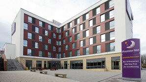 Ein Premier Inn Hotel mit modernem Design, das einen großzügigen Eingangsbereich, eine Außenbereich-Sitzgelegenheit und eine Schilderung mit Annehmlichkeiten wie Bar und Restaurant, kostenlose Unterbringung für Kinder sowie Klimaanlage bietet.