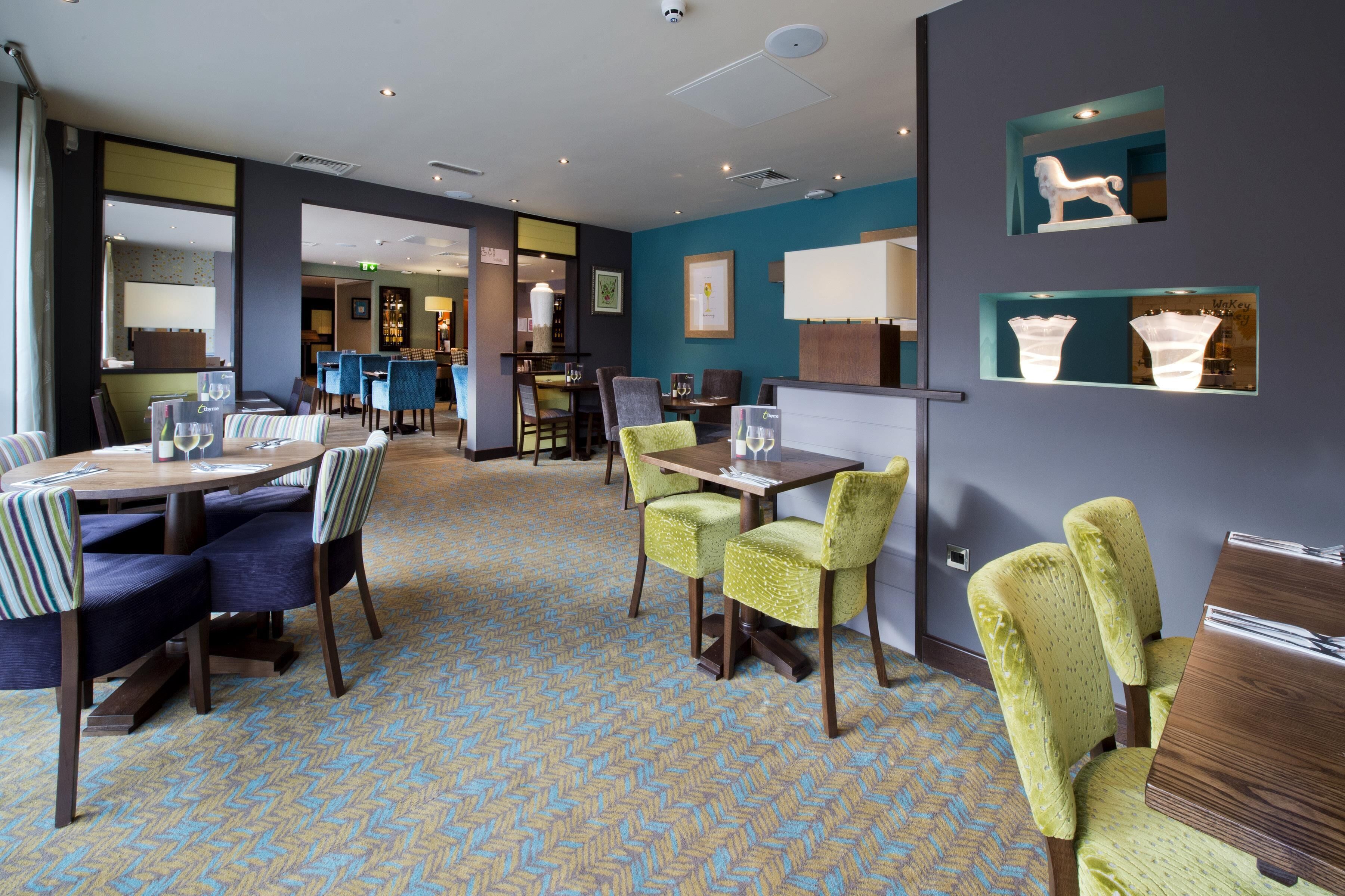 A hotel lobby with a herringbone patterned floor, a bar area, and seating arrangements.
