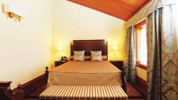 A hotel room with a large bed, two bedside tables, and a bench at the foot of the bed.