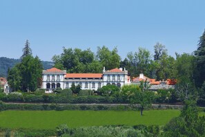 A large, historic building with a red-tiled roof, surrounded by lush greenery and a well-maintained lawn. - Parador Casa da Insua (Penalva Do Castelo)