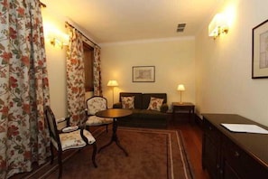A room with a sofa, chairs, a small table, a desk, and a lamp. - Parador Casa da Insua (Penalva Do Castelo)