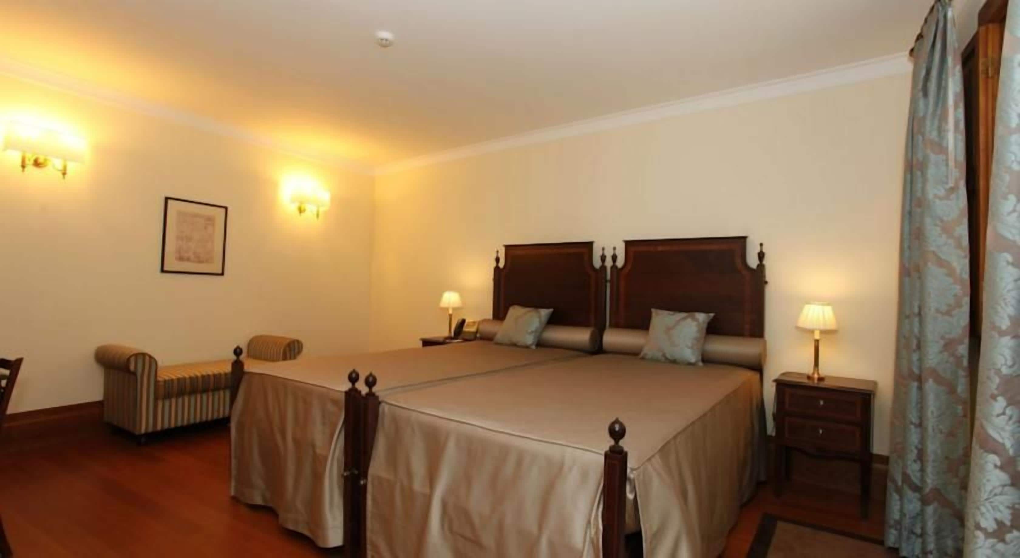 Ein Hotelzimmer mit einem großen Bett, einem Sessel, einem Nachttisch und einer Lampe.