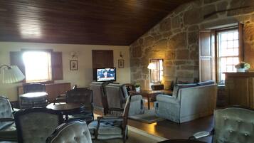 A cozy living room with stone walls, a television, comfortable seating, and a fireplace.