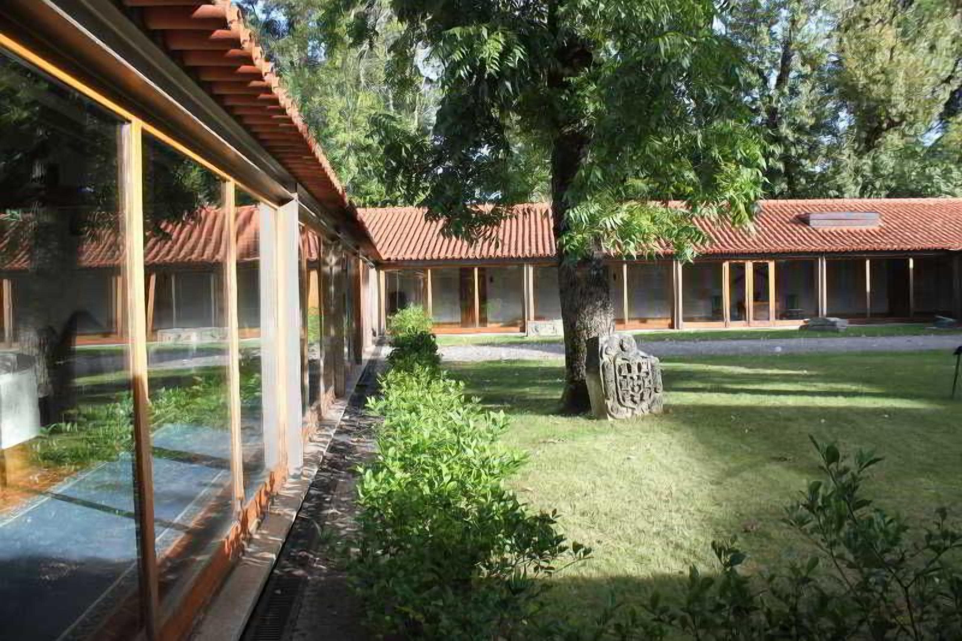 A building with a glass facade, a red-tiled roof, and a well-maintained lawn.