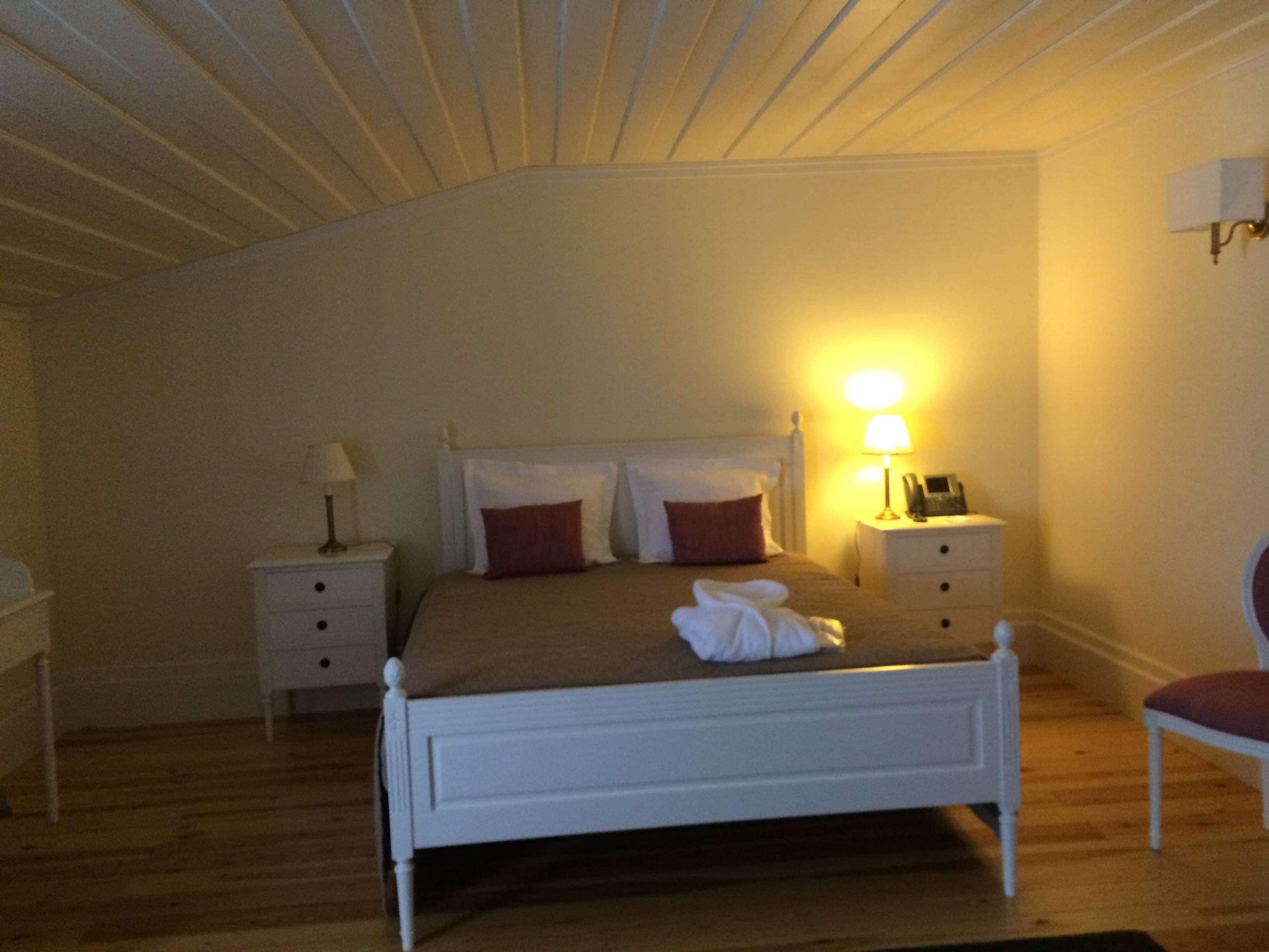 A bedroom with a bed, bedside tables, a lamp, and a chair.