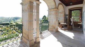 A balcony with stone columns, a wrought iron railing, and a view of a green landscape. - Parador Casa da Insua (Penalva Do Castelo)