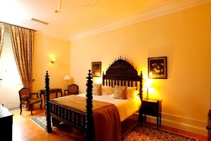 A bedroom with a four-poster bed, a wooden floor, a patterned rug, and two bedside tables with lamps. - Parador Casa da Insua (Penalva Do Castelo)