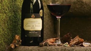 A bottle of Casa da Ínsua Dão wine and a glass of red wine on a stone surface with moss-covered walls. - Parador Casa da Insua (Penalva Do Castelo)