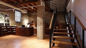 A spacious room with a wooden staircase, stone pillar, and a wine rack. - Parador Casa da Insua (Penalva Do Castelo)