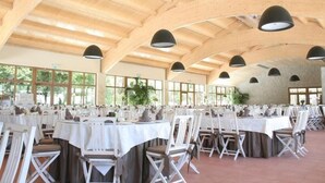 A spacious indoor venue with high ceilings and natural light from large windows. Tables are set with white tablecloths and chairs, arranged for a formal event. - Parador Casa da Insua (Penalva Do Castelo)