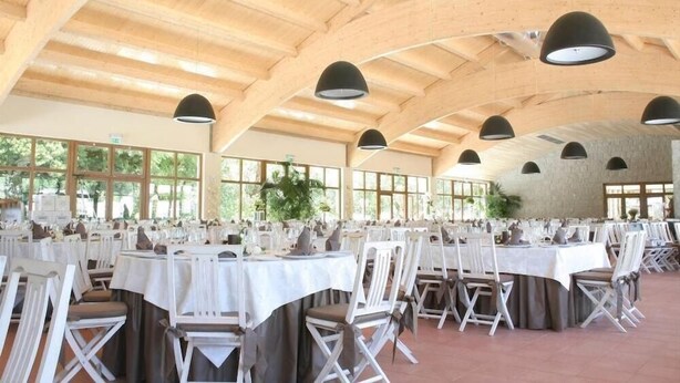 A spacious indoor venue with high ceilings and natural light from large windows. Tables are set with white tablecloths and chairs, arranged for a formal event. - Parador Casa da Insua (Penalva Do Castelo)