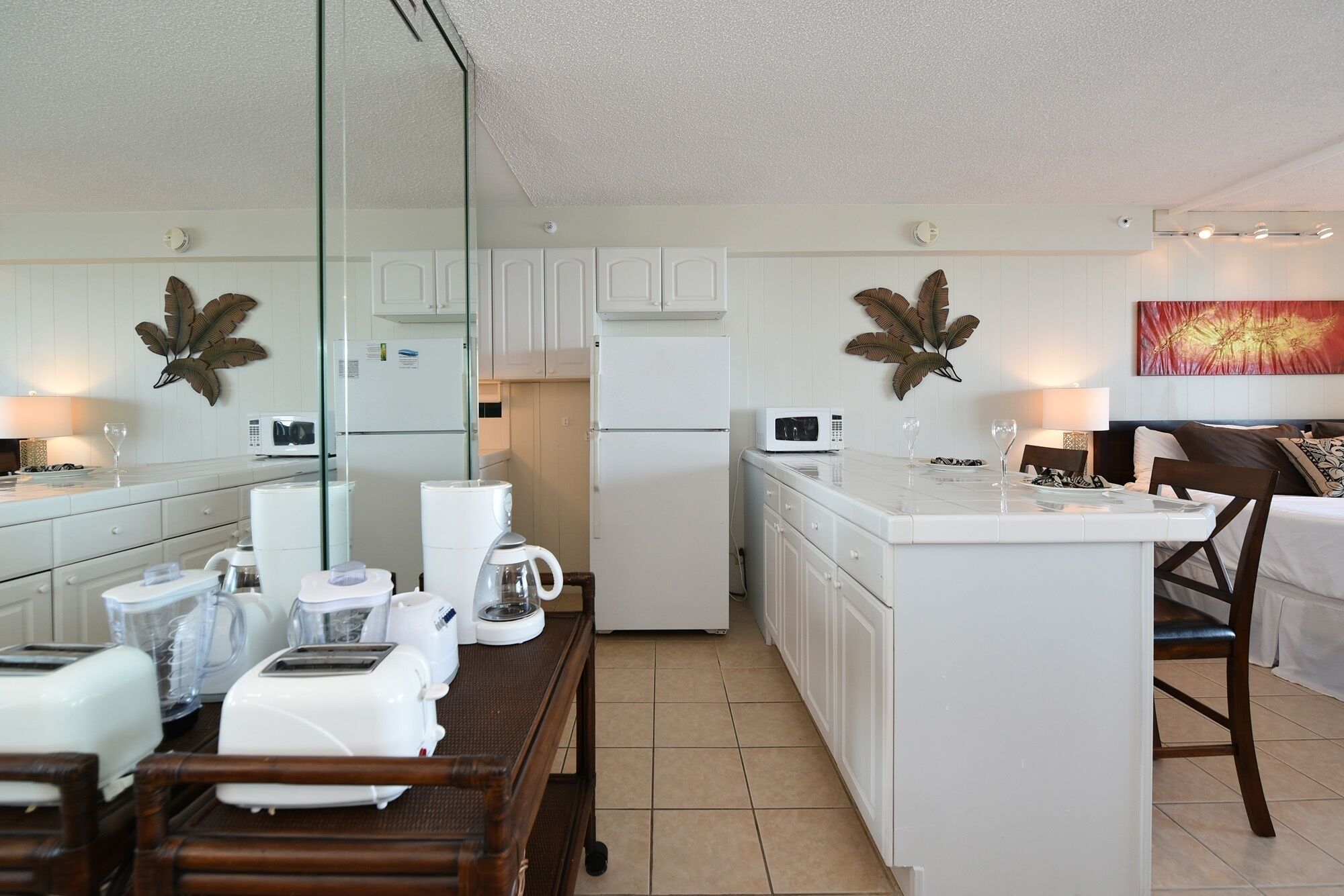 A modern kitchen with white cabinets, a central island, and a dining area with wooden chairs.