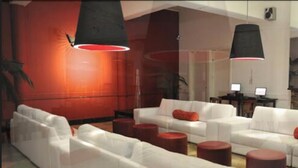 Una sala moderna con sofás blancos y detalles en rojo, con un ventanal grande y una chimenea.