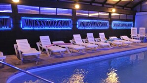 Una piscina con sillas de descanso y una pared iluminada en azul con texto.