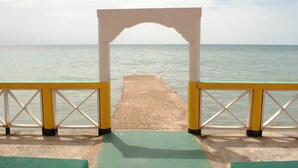 A pier leading to a body of water with a white archway and yellow railings. - Bluefields on the Bay (Bluefields)