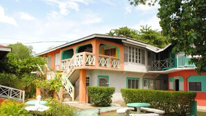 A two-story building with a balcony, a staircase, and a small garden area with a table and benches. - Bluefields on the Bay (Bluefields)