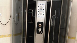 Box de chuveiro com painel de controle, chuveiro manual e porta-toalhas.