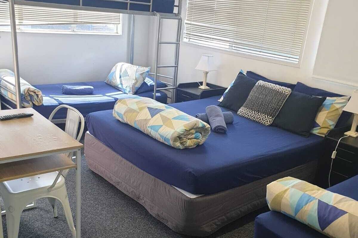 Um quarto em dormitório com beliches, escrivaninha e cadeira.