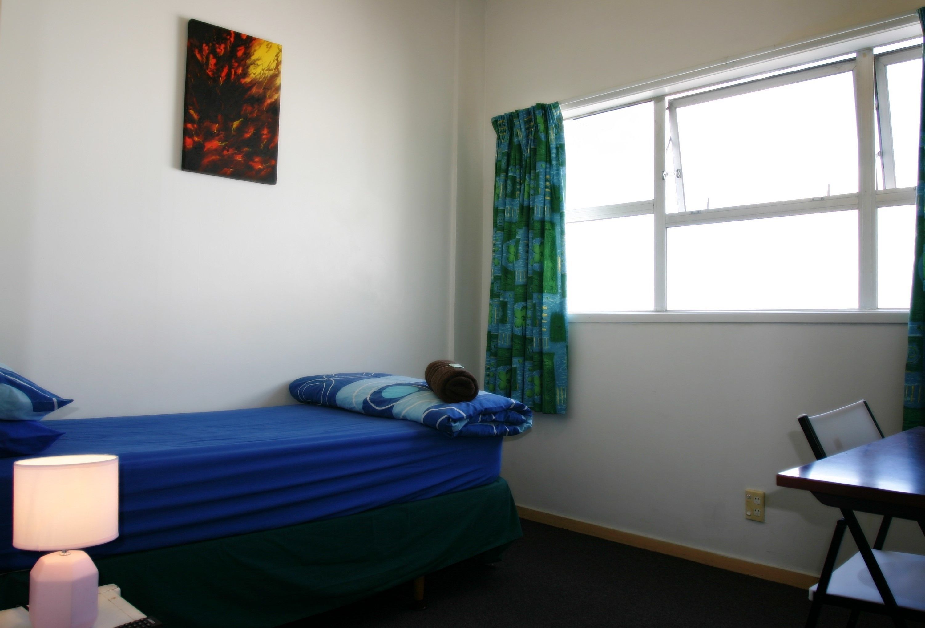 Una habitación con una cama, una mesa y un ventanal con cortinas.