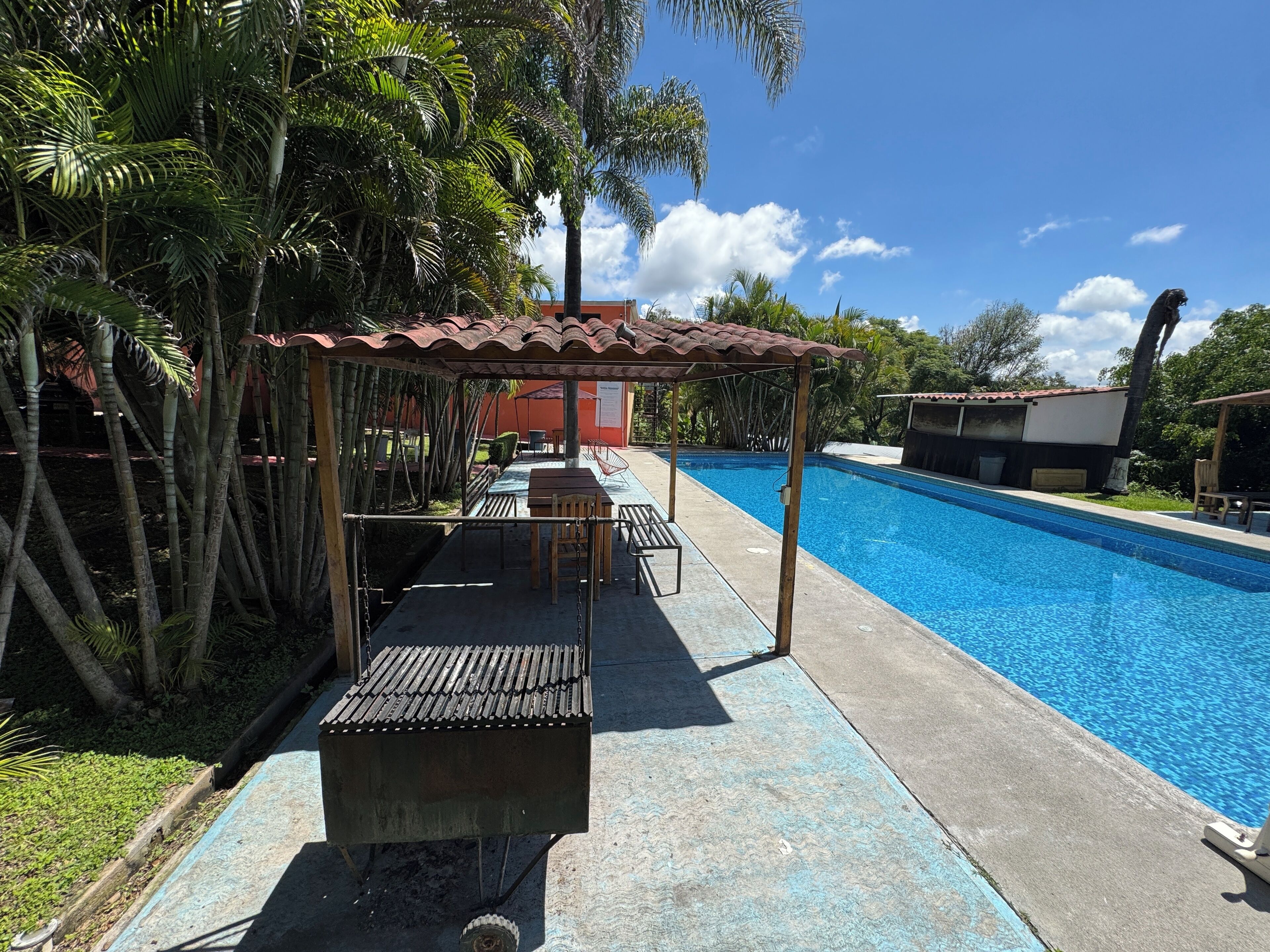 A poolside area with a covered seating area, a grill, and a pool.