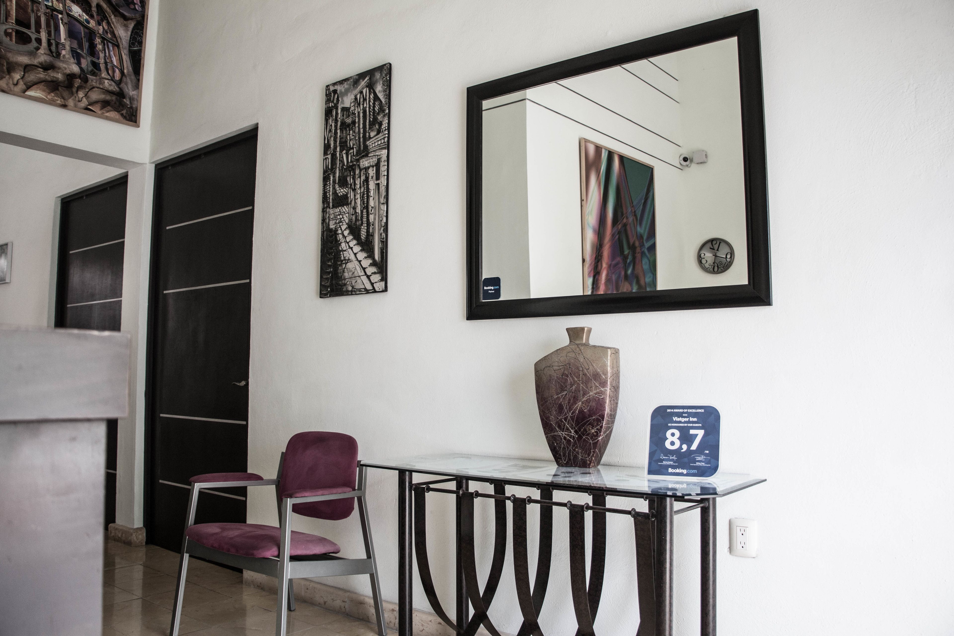 A hotel lobby with a modern design, featuring a marble table, a large mirror, and artwork on the walls.