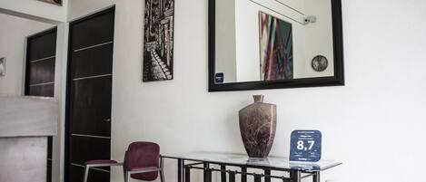 A hotel lobby with a modern design, featuring a marble table, a large mirror, and artwork on the walls.