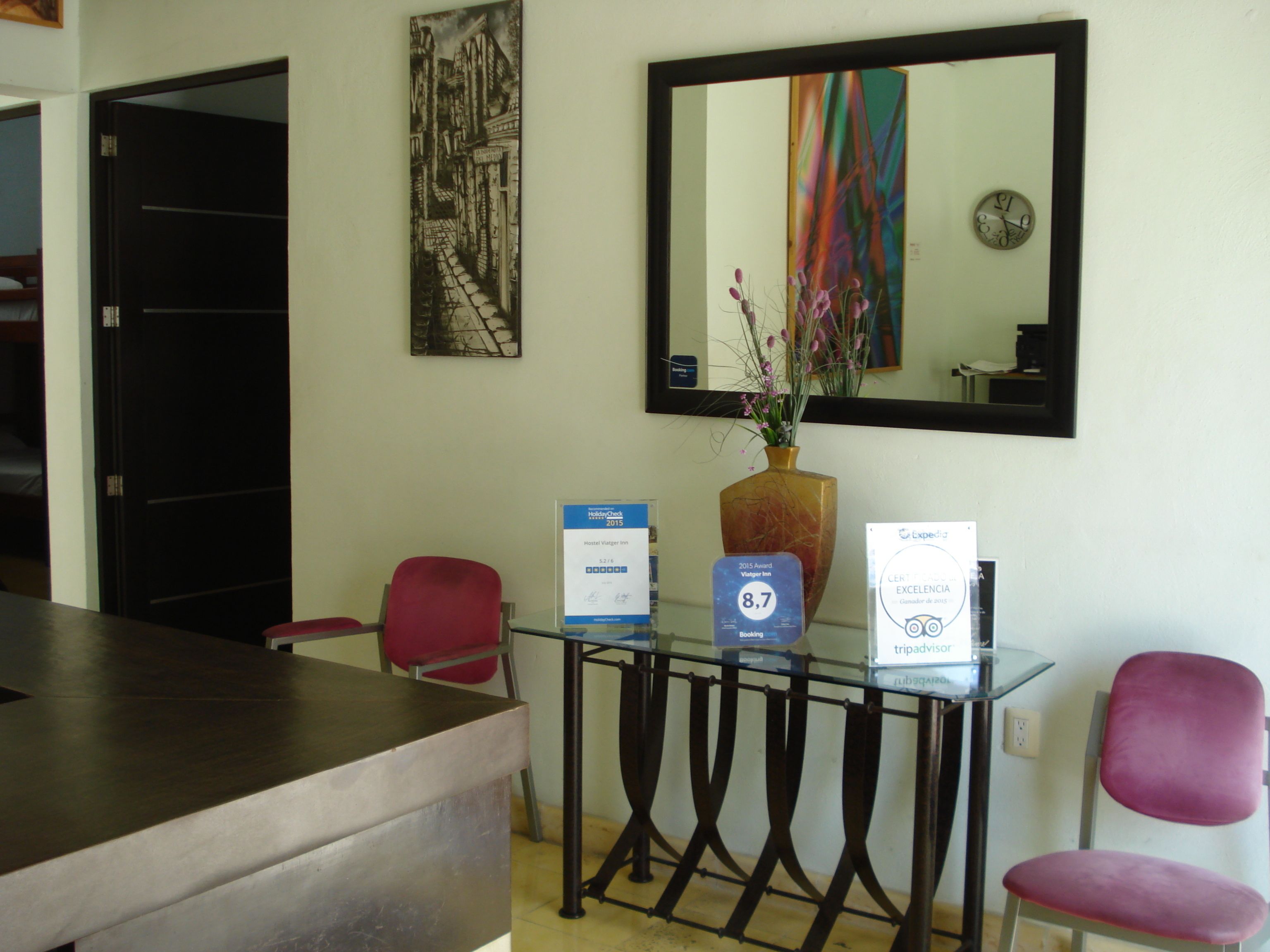 Un mostrador de recepción con encimera de vidrio, un jarrón con flores y premios para el hotel.