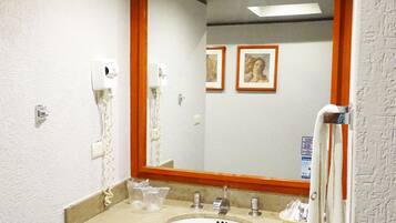 Un baño con lavamanos, espejo y perchero para toallas.