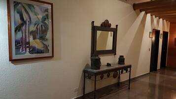 Un pasillo con un cuadro enmarcado, un espejo y una pequeña mesa con objetos decorativos.