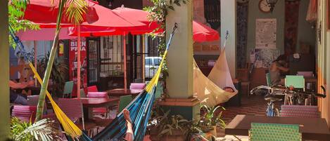 An outdoor seating area with tables and chairs, a hammock, and potted plants.