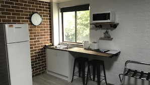 A compact kitchen with a refrigerator, a sink, a microwave, and a window providing natural light.