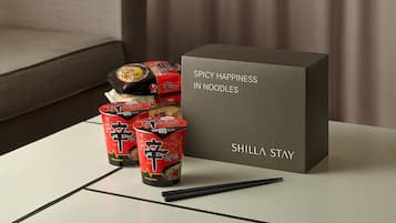 A table with a box labeled 'SPICY HAPPINESS IN NOODLES' and several red and black packaged food items.