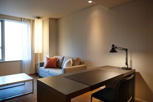 Una sala moderna con un sofá, un escritorio y una lámpara.