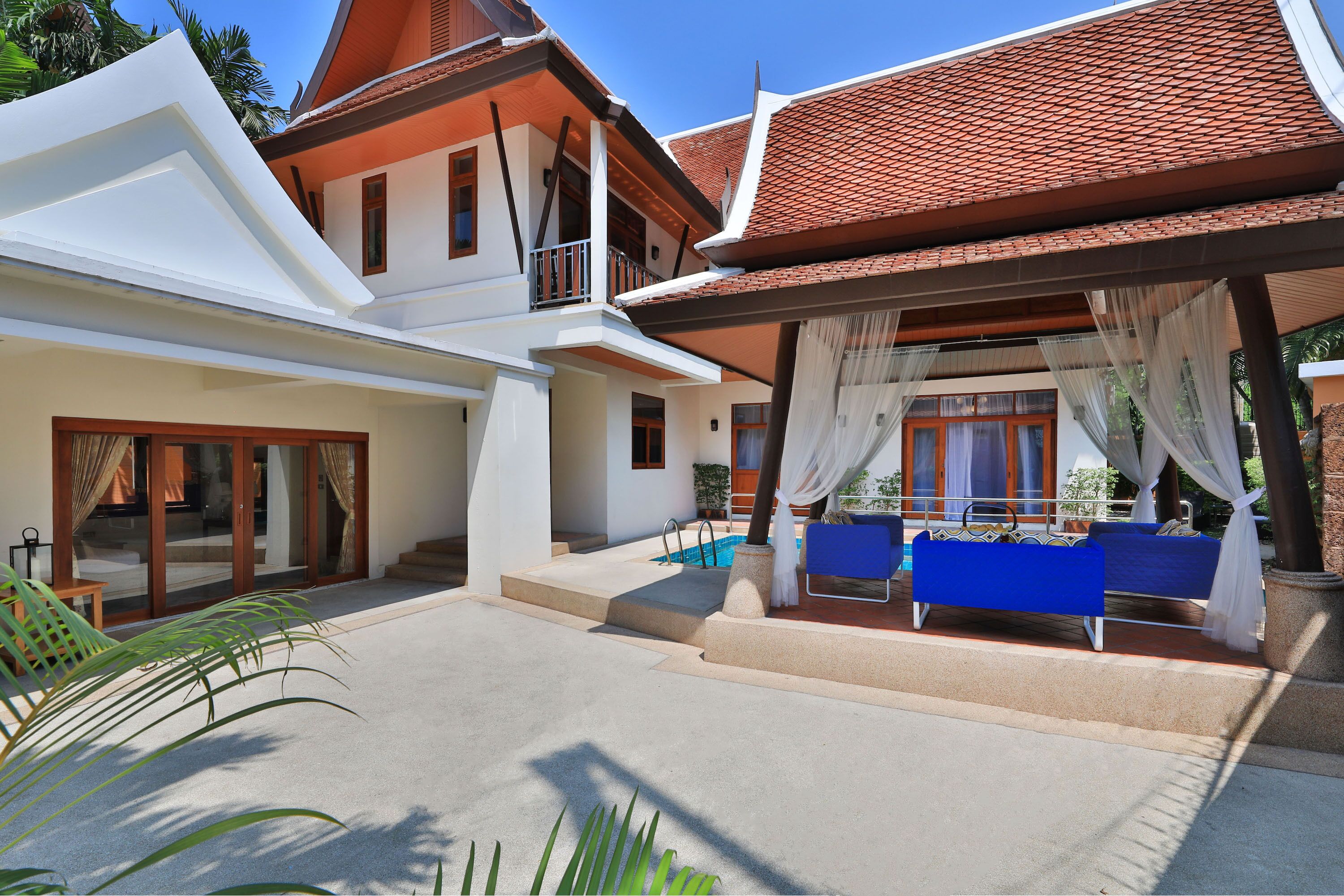 A modern villa with a swimming pool, outdoor seating, and a covered patio area.