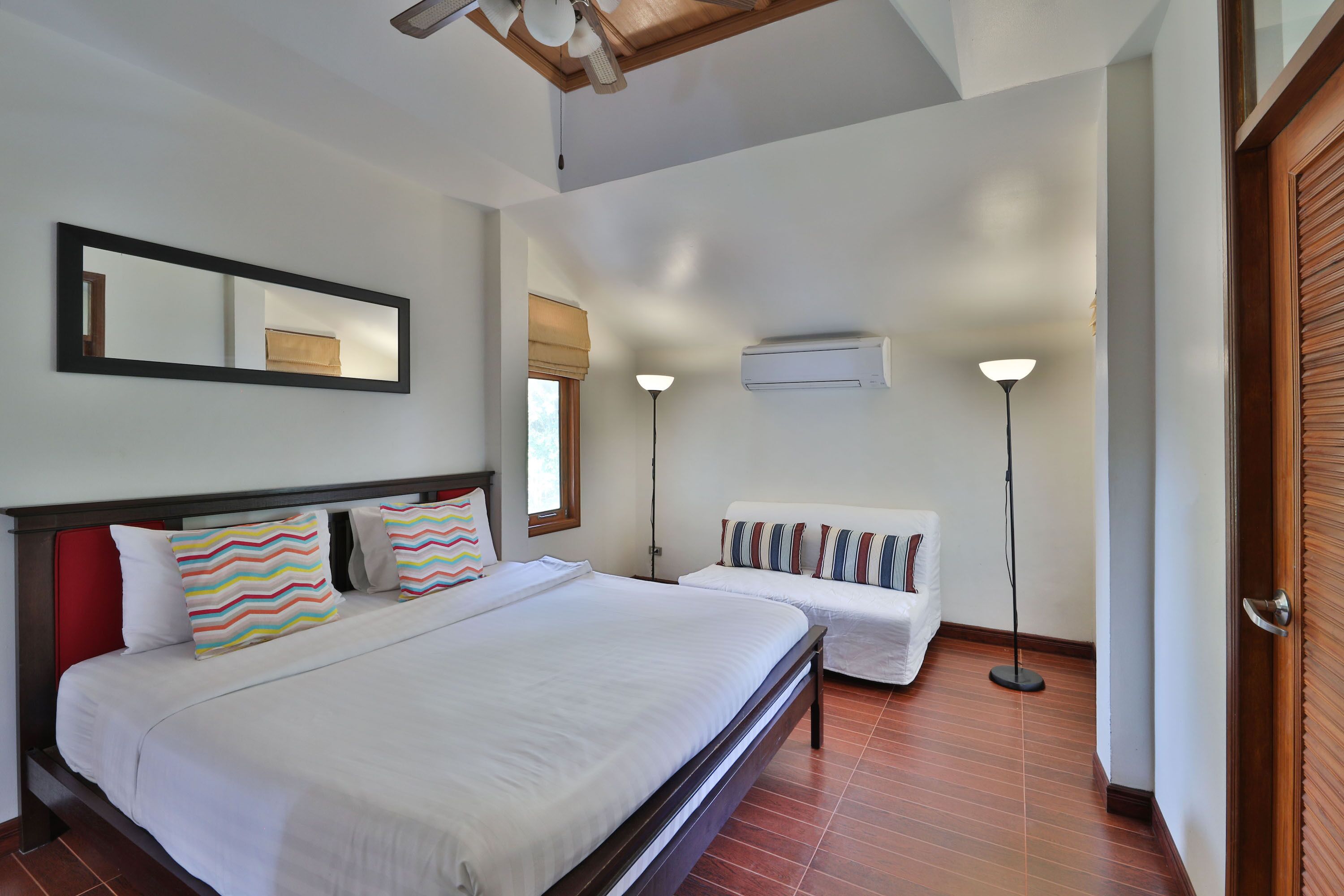 Habitación de hotel con una cama grande, una mesita de noche, una silla, un espejo y una ventana con vistas.