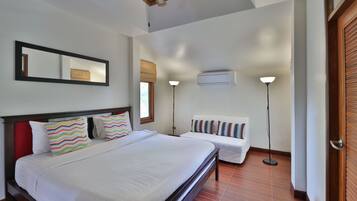 Habitación de hotel con una cama grande, una mesita de noche, una silla, un espejo y una ventana con vistas.