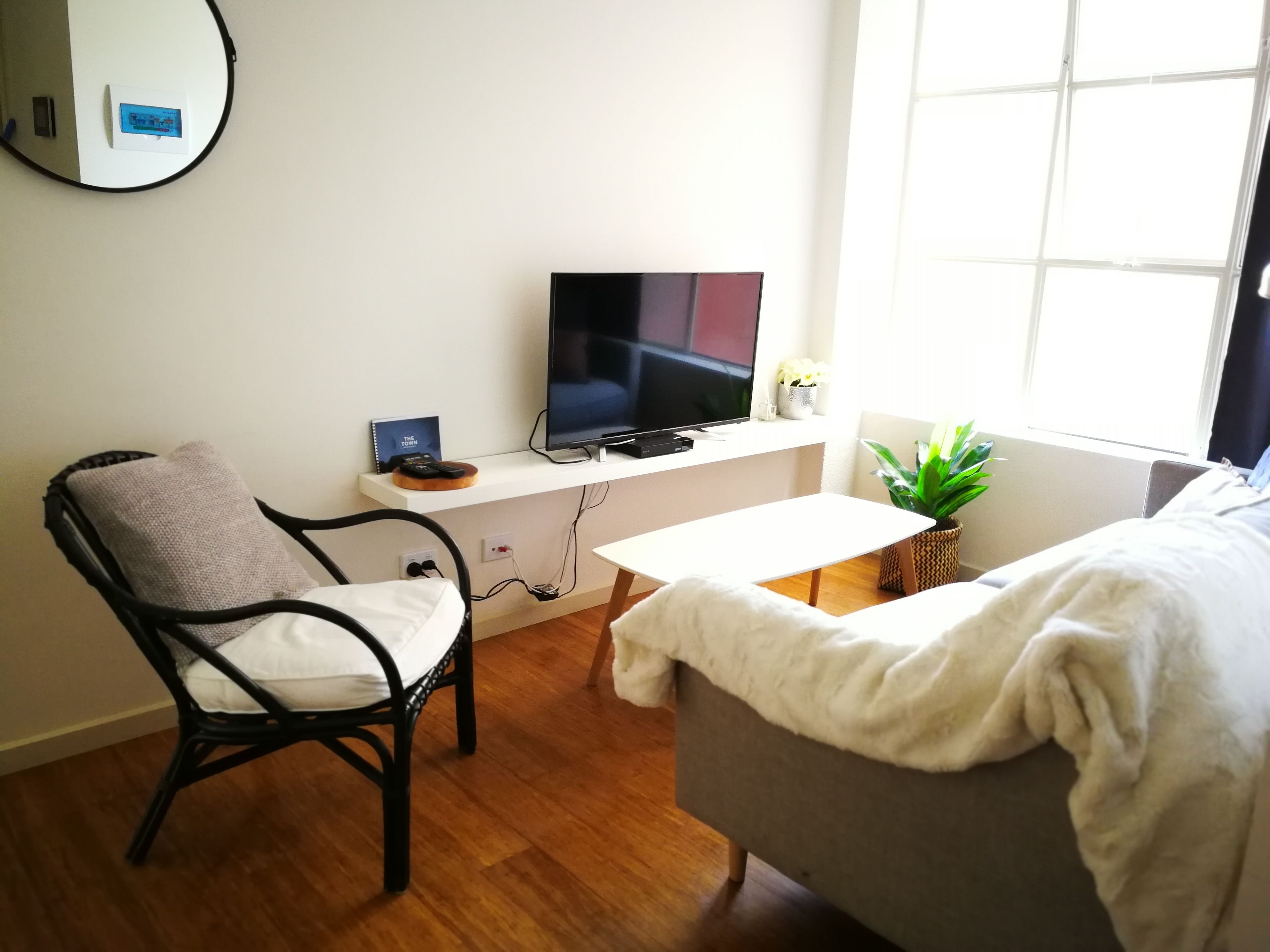 Una sala de estar moderna con una televisión, un sofá, un sillón y una mesita.