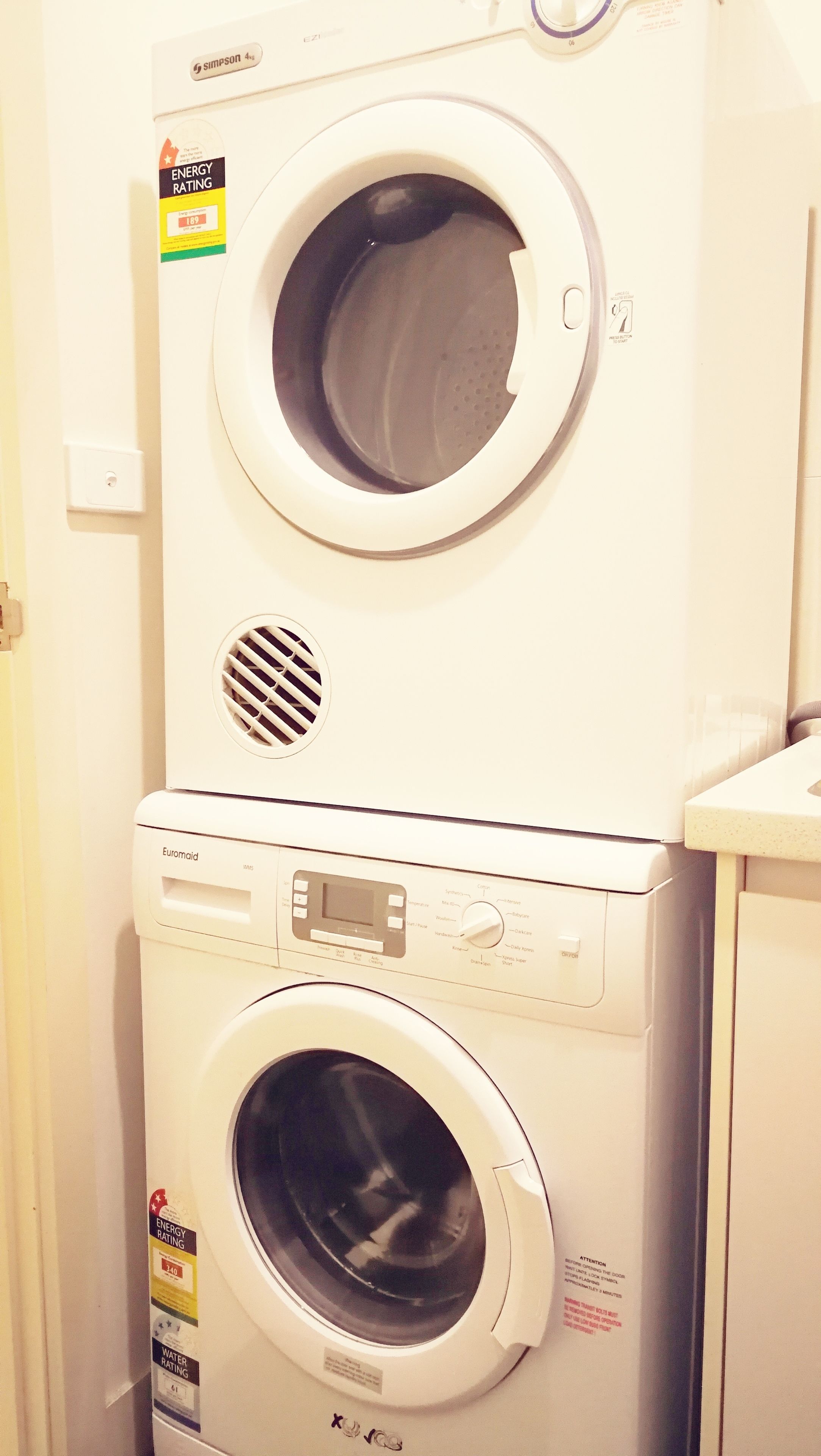 A front-loading washer and dryer stacked in a laundry room.