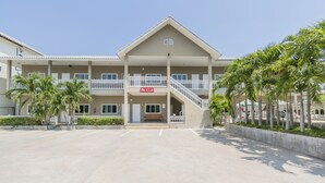 A hotel with a central entrance, multiple balconies, and palm trees. - Pom Pom Residence (Hua Hin)