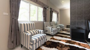 A living room with striped sofas, a fireplace, and a patterned rug. - Pom Pom Residence (Hua Hin)
