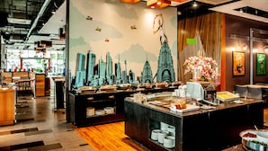 A buffet area with a cityscape mural, wooden flooring, and a variety of food items. - FEECO HOTEL KUALA LUMPUR (Kuala Lumpur)