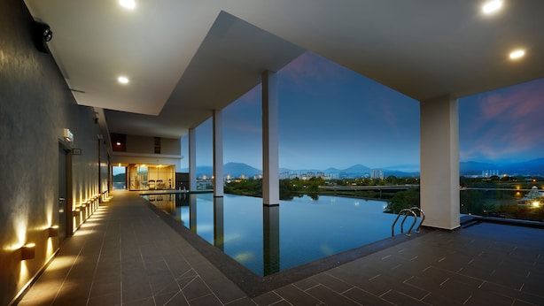 A modern hotel pool area with a view of mountains and cityscape at dusk. - FEECO HOTEL KUALA LUMPUR (Kuala Lumpur)