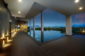 Ein moderner Hotelpoolbereich mit Blick auf Berge und Stadtbild in der Abenddämmerung.