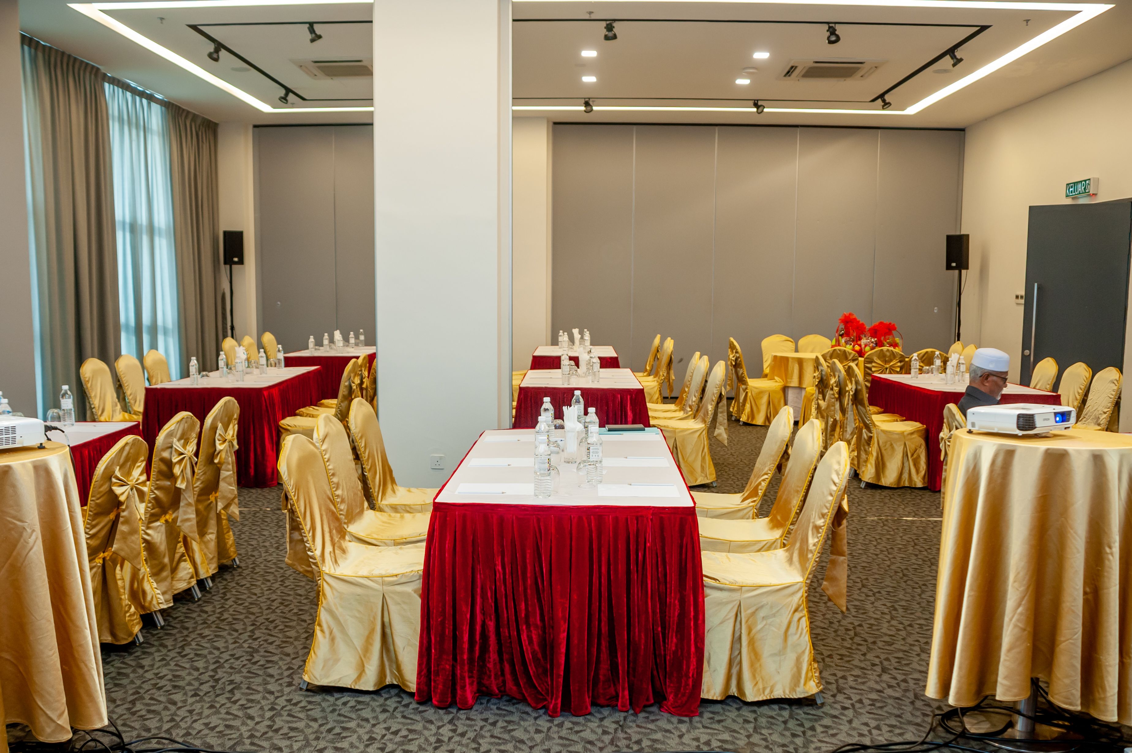 A conference room with tables set for a meeting, equipped with microphones and projectors.