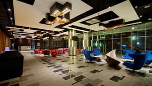 A modern lobby with a mix of seating areas, including blue and red chairs, and a patterned floor. - FEECO HOTEL KUALA LUMPUR (Kuala Lumpur)