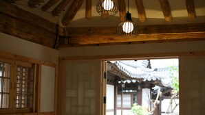 A traditional Japanese room with wooden beams, tatami flooring, and a view of an outdoor garden. - Gaeunchae (Jeonju)