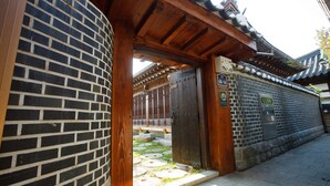 A traditional Japanese building with a wooden entrance, a brick wall, and a tiled roof. - Gaeunchae (Jeonju)